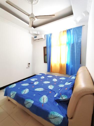 a bed in a room with a blue comforter at Kwa Mzungu Villa in Nungwi