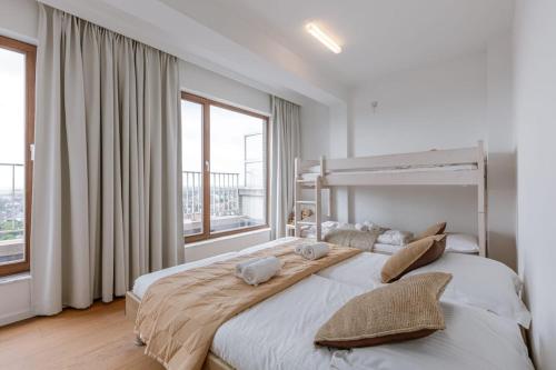 a large white bedroom with a large bed and windows at Seahouse by BLOSS, seafront duplexappartement in Wenduine
