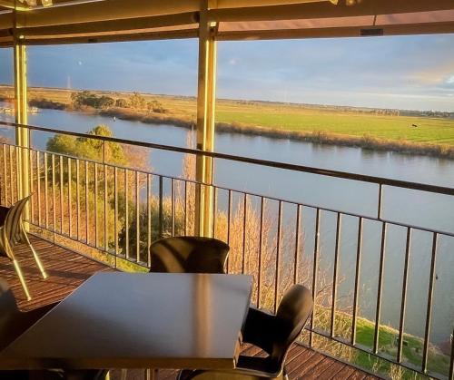 a balcony with a table and chairs and a view of a river at Tailem Bend Riverside Hotel in Tailem Bend