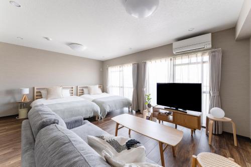 a hotel room with two beds and a couch and a tv at Planetarium N in Yamashitachō