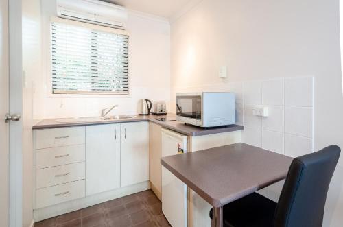 una pequeña cocina con mesa y microondas en Central Studio Accommodation, en Gladstone