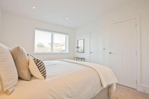 a white bedroom with a bed and a window at Fellbeck Holiday Home - Cartmel in the Lake District in Cartmel