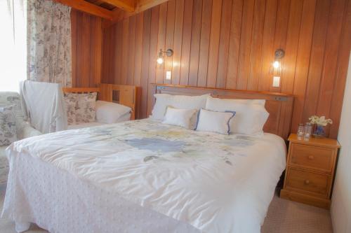 a bedroom with a large white bed with wooden walls at Okoroire Hot Springs Hotel in Okoroire