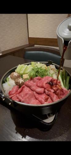 a pan filled with meat and vegetables on a table at Yoshidaya Ryokan よしだや in Nara