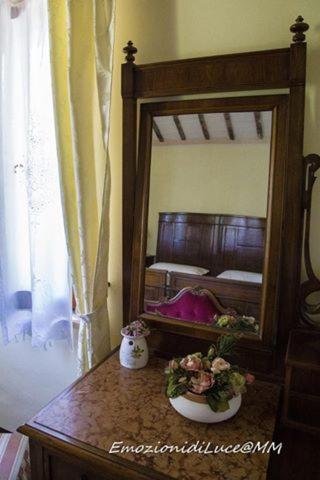 a table with a mirror and flowers on it at B&B Il Giardino in Tavullia