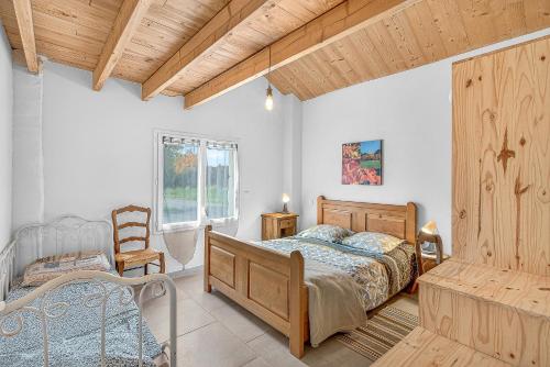 a bedroom with a bed and a chair and a window at Gîte La Grange Des Pépinières in Saint-Auban-dʼOze
