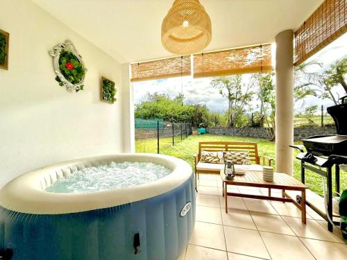 a large blue tub in a living room with a piano at Le Kerbo, Calme & Jacuzzi privé à Bras-Panon in Bras-Panon
