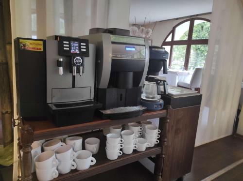 Una cafetera con tazas de café en un estante. en Hôtel La Rivière, en Entraygues-sur-Truyère