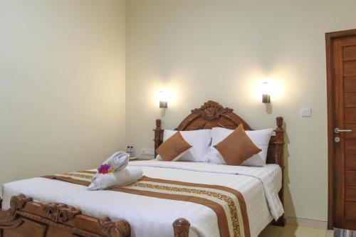 a bedroom with a large bed with a wooden headboard at D'Waktu in House in Nusa Lembongan