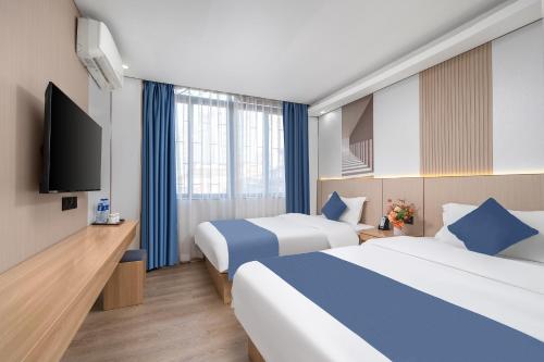 a hotel room with two beds and a flat screen tv at Yinuo Hotel - Guangzhou Shangxiajiu Pedestrian Street, Yongqingfang Branch in Guangzhou