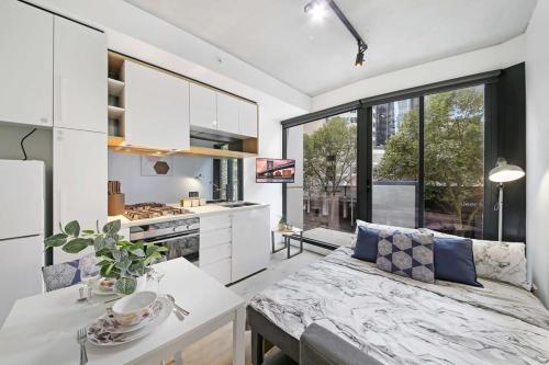 a kitchen and living room with a couch and a table at Bright & Modern 2BR Apt Walk to Central in Melbourne