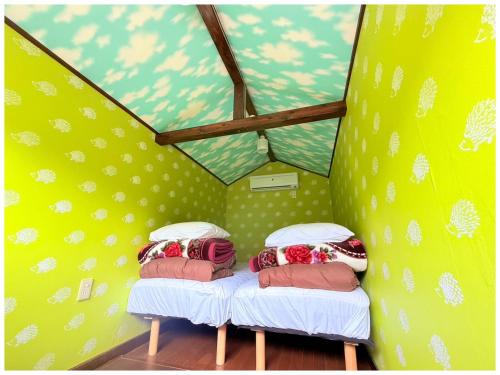 two beds in a small room with yellow walls at コテージそら豆ん家 in Nasu