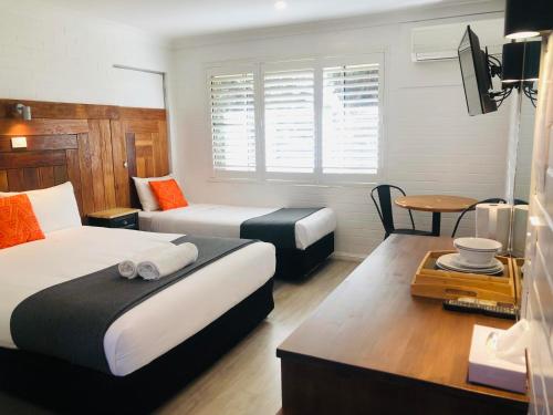 a hotel room with two beds and a table at Pleasant Way River Lodge in Nowra
