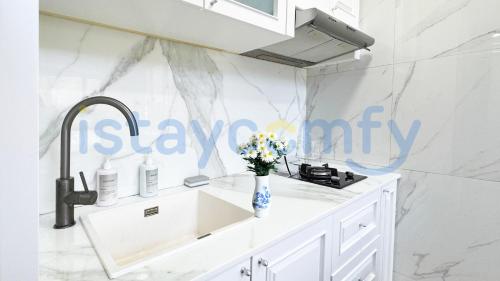a white kitchen with a sink and a vase of flowers at 3BR One Residence 1AL 2 Level with Stair Sea and City View in Pulau Sembakau Kecil