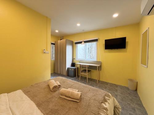 a bedroom with yellow walls and a bed and a desk at Il Piccolo Paradiso - Hôtel in Koh Samui