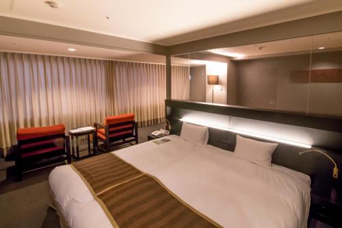 a bedroom with a large white bed and chairs at Hotel Epinard Nasu in Nasu