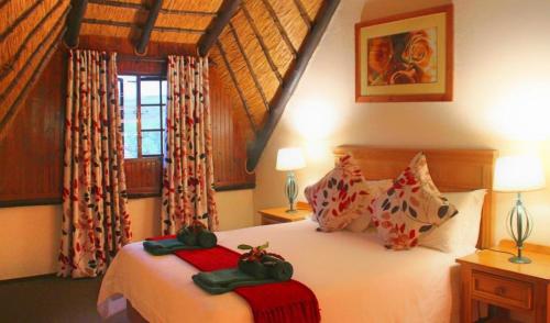 a bedroom with a bed and a window at Fairways Resort Drakensberg in Drakensberg Garden
