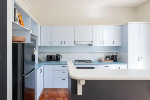 eine weiße Küche mit weißen Schränken und einem schwarzen Kühlschrank in der Unterkunft 3 Bed Close To City Adelaide Oval Golf Course in North Adelaide