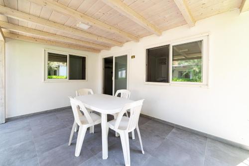 a white dining room with a white table and chairs at Villaggio Capo Vieste in Vieste