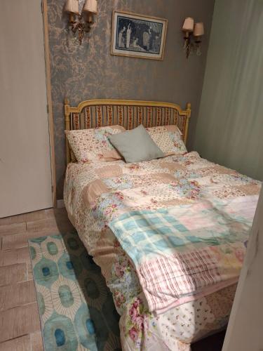 a bed with a quilt and a pillow on it at Appartement de charme plein centre in Libourne