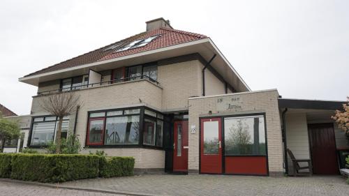 a house with a red door and windows at Logies Jardin Schagen in Schagen