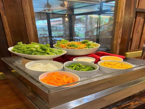 ein Buffet mit Schüsseln mit Gemüse und anderen Speisen in der Unterkunft Borneo Beach & Mangrove Resort in Tuaran