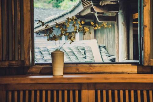 a vase sitting on a window sill with a view at Tsingpu Tulou Retreat 青普文化行馆 南靖土楼店 in Nanjing