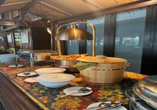 ein Buffet mit Schalen und Geschirr auf dem Tisch in der Unterkunft Borneo Beach & Mangrove Resort in Tuaran