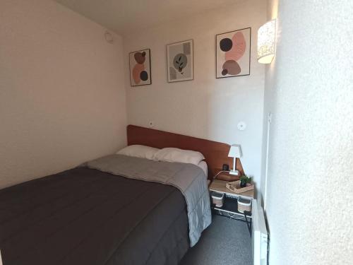 a small bedroom with a bed and two pictures on the wall at À deux pas des pistes in Aragnouet