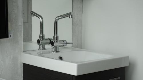 a white bathroom sink with two faucets on it at Logies Jardin Schagen in Schagen