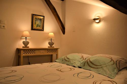 a bedroom with a bed and a table with two lamps at Le Gite Des Ecureuils in Pinet