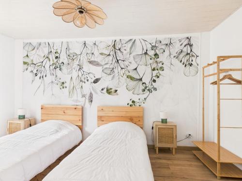 Un dormitorio con dos camas y una pared con un mural de flores. en Jolie maison pour 4 à proximité du centre, en Montignac