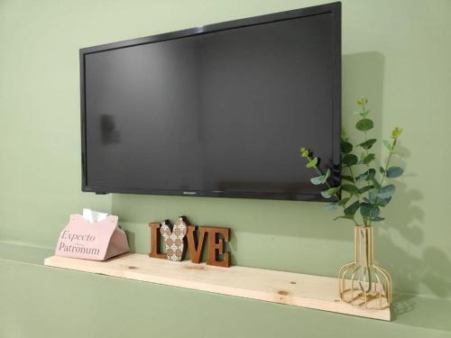 a flat screen tv on a wall with a shelf at Suite Us Guesthouse Kubang Kerian in Kota Bharu