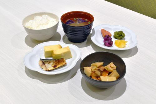 a table with plates of food and bowls of food at Asahikawa Sun Hotel in Asahikawa