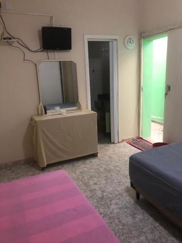 a bedroom with a mirror and a table with a bed at Suites Pitangueiras in Guarujá