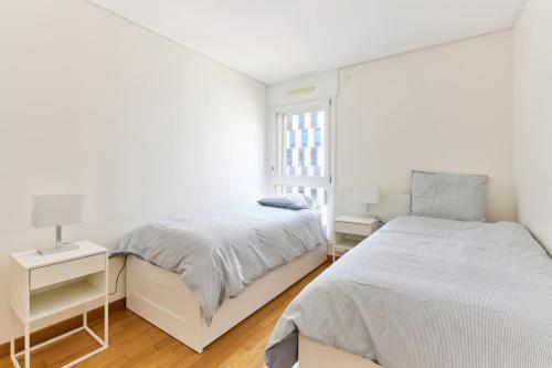 a white bedroom with two beds and a window at Bright apartment paris 19-metro 7 in Paris