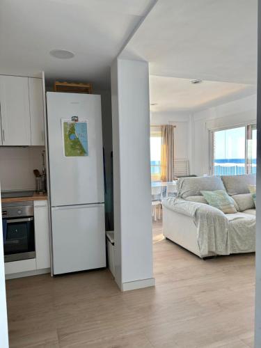 a living room with a white refrigerator and a couch at Mareny de Barraquetes in Mareny Blau