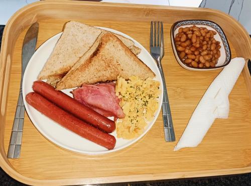 Een bord met ontbijtproducten zoals worst, eieren, brood en bonen. bij Duplessis Lodge in Kempton Park