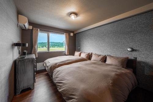 two beds in a room with a window at The Horizon Residence in Makubetsu