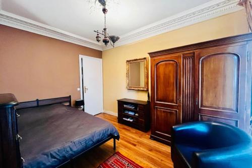 a bedroom with a bed and a cabinet and a chair at 16th 10 minutes from the Eiffel Tower Metro line 9 in Paris