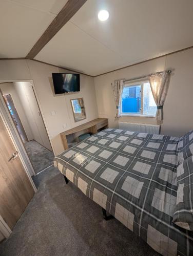 ein Schlafzimmer mit einem Bett und einem Fernseher an der Wand in der Unterkunft Elegant caravan home in Hampshire, United Kingdom 6 guests 2 bedroom 3 beds 1 sofa bed 2bathrooms in Hayling Island
