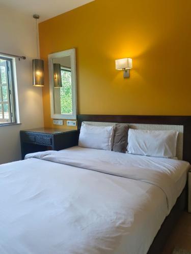 アーポラにあるHotel Coco Goaのベッドルーム1室(黄色い壁の大きな白いベッド1台付)