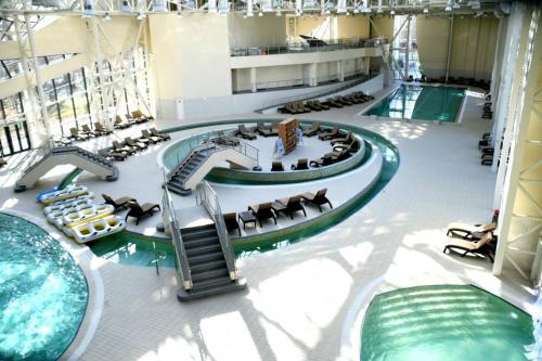 a large indoor pool with chairs and a swimming pool at Aqua Studio Craiova in Craiova
