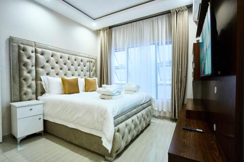 a bedroom with a large bed with a large window at The Mendel Boutique Residence in Harare