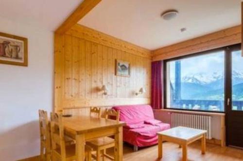 a living room with a table and a pink couch at Résidence & Spa La Grande Cordée - Combloux in Combloux