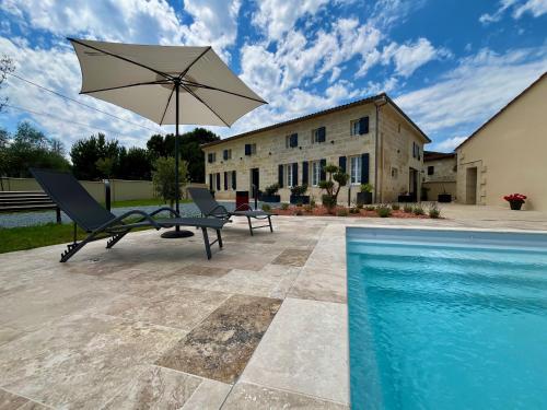 a patio with two chairs and an umbrella next to a swimming pool at Le Loft By Repaire de Maltus in Lussac