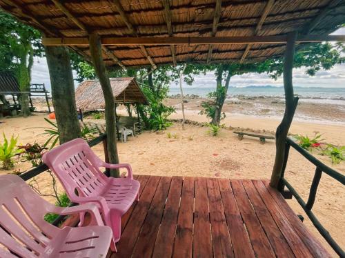 ジュム島にあるSunset Beach Bungalow Koh Puのビーチ近くの木製デッキに置かれた2脚の椅子