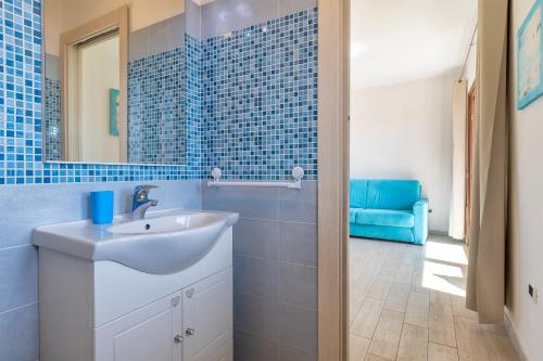 a blue tiled bathroom with a sink and a mirror at La Finestra sul Mare in Isola Rossa