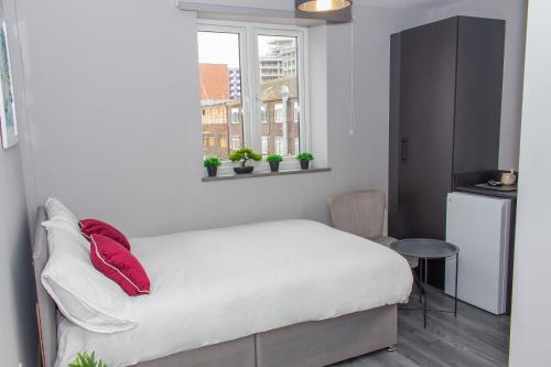 ein Schlafzimmer mit einem Bett mit roten Kissen und einem Fenster in der Unterkunft Mammut House in Liverpool