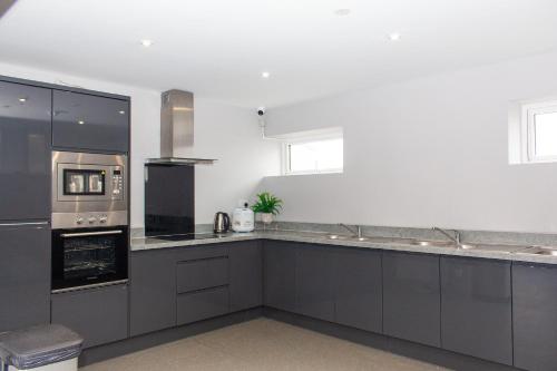 eine Küche mit grauen Schränken und einem Herd mit Backofen in der Unterkunft Mammut House in Liverpool